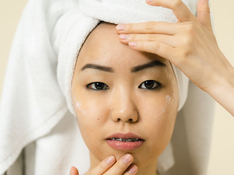 Người phụ nữ châu Á kiểm tra làn da nhạy cảm trước gương