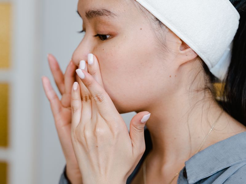 Phụ nữ châu Á làm sạch và chăm sóc da mụn trứng cá tại nhà