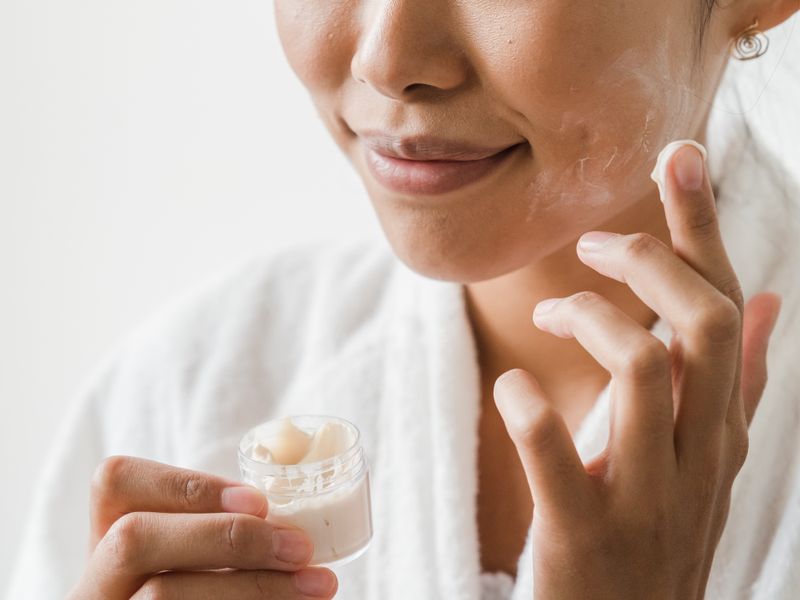 Phụ nữ châu Á thoa kem dưỡng ẩm chăm sóc da thiếu nước tại nhà