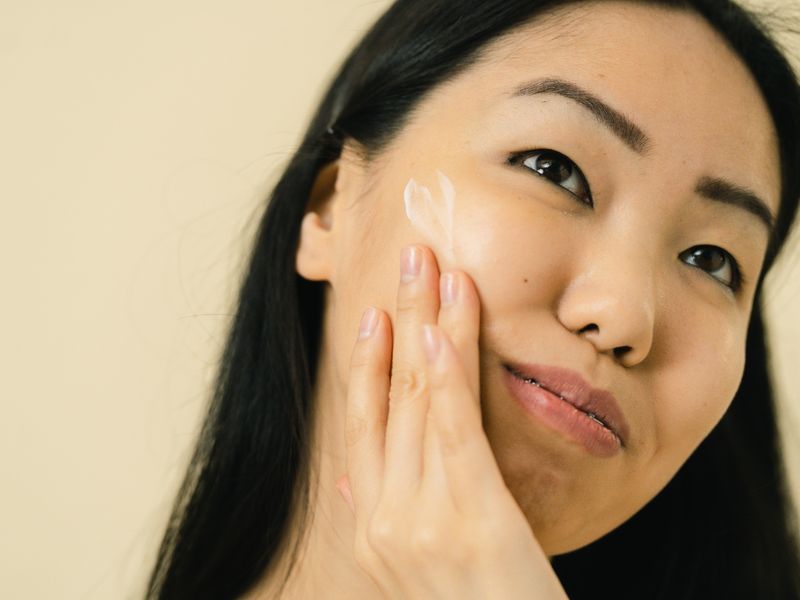 Cô gái châu Á thoa kem dưỡng dịu nhẹ cho da nhạy cảm