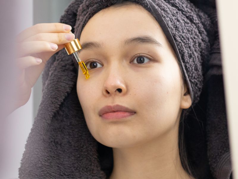 Cô gái châu Á thoa serum peptide trong mỹ phẩm chăm sóc da mặt